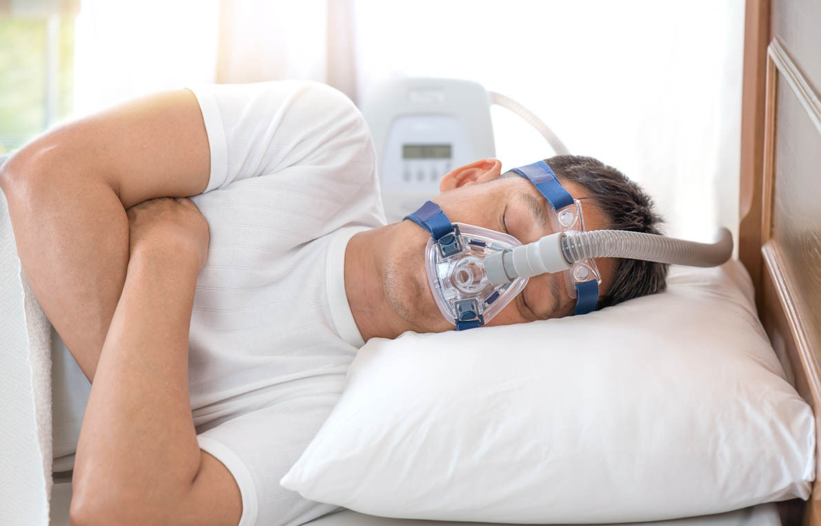 Man sleeping in bed wearing CPAP mask ,sleep apnea therapy<br />
Happy